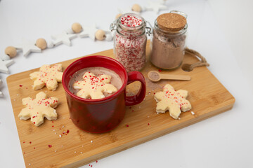 Hot Chocolate in a Red Cup with Snowflake-Shaped Marshmallows with Jars of Peppermint Candy and Hot Chocolate in Background
