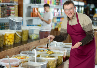 Male supermarket grocery seller offers to buy pickled green olives