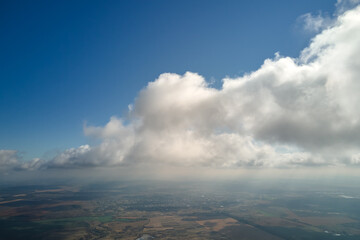 Aerial view from airplane window at high altitude of earth covered with puffy cumulus clouds...