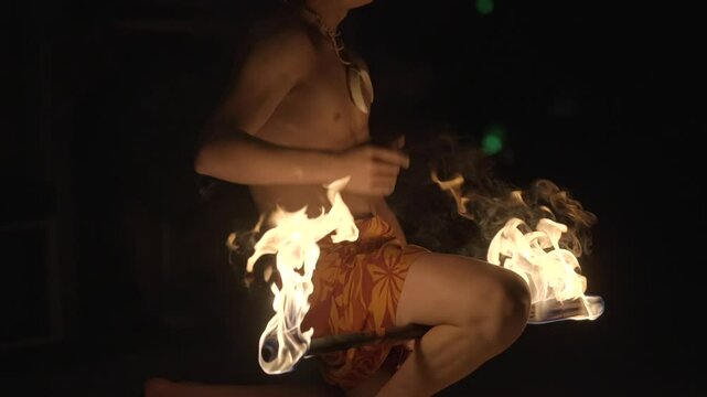 Polynesian poi fire dancer spinning flaming torches at night, creating vivid light trails against a dark sky. Perfect for themes of tradition, performance, or dramatic visual storytelling.