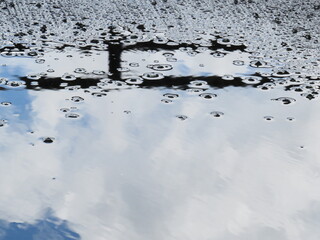 El reflejo de las nubes se ve en el agua en un estacionamiento. El viento movía el agua.
El...