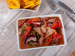 Treat for guests of restaurant of national Latin American cuisine is ceviche made of fish and fresh vegetables, complemented by bowl of fried bananas plantains