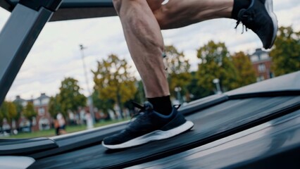 Close up of muscular legs running intensely on treadmill within urban park setting, capturing raw athletic performance and unwavering commitment to personal fitness goals