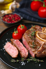 Pieces of delicious beef meat, spices and tomatoes on table, closeup