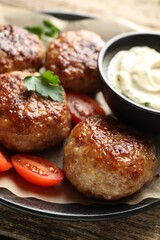Delicious patties, parsley, tomatoes and sauce on wooden table, closeup