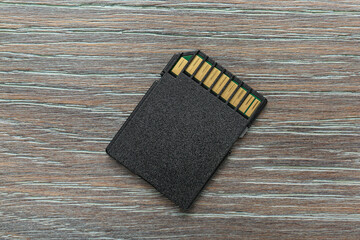 One SD memory card on grey wooden table, top view