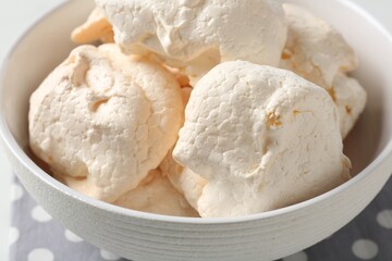 Delicious homemade meringue cookies in bowl on table, closeup