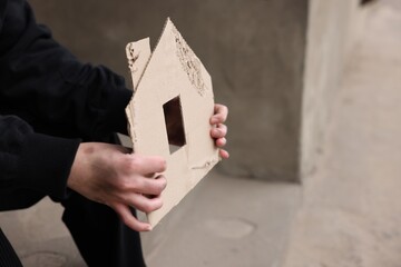 Homeless man with carton house figure outdoors, closeup