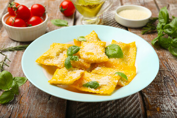 Delicious ravioli with cheese and basil served on wooden table, closeup