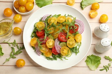 Fresh salad with yellow tomatoes on white wooden table, flat lay