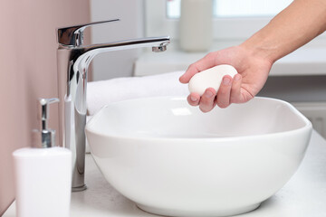 Woman with soap above sink in bathroom, closeup