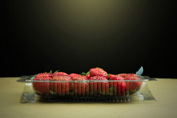 Fresh Red Strawberries in Plastic Container on Tan Surface