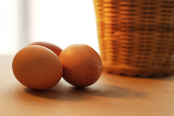 Three Eggs Near Basket On Beige Table In Warm Light