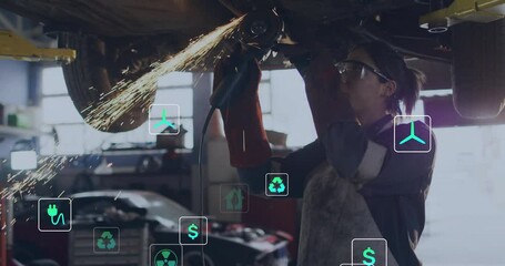 female mechanic using angle grinder beneath car in auto workshop, showing floating energy icons - Powered by Adobe