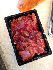 carpaccio di tonno servito in una guantierina di plastica sul banone di una pescheria