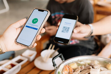 Selective focus to QR code tag with blurry smartphone display the payment page has been completed. Scan QR code payment. QR code tag  payment with blurry grilled pork and meat on the stove.