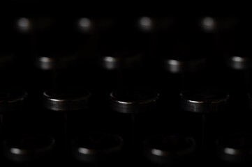 Abstract edge of typewriter keys highlighted against a black background