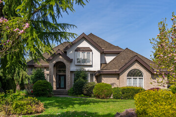 Two story stucco luxury house with nice spring blossom landscape in Vancouver, Canada, North America. Day time on April 2025.