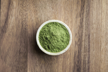  Kale Powder in ceramic bowl on a wooden background, top view