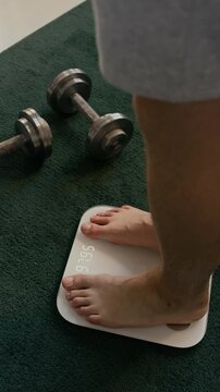 Vertical shot of unrecognizable man stepping on scale to check his weight during sitting on diet