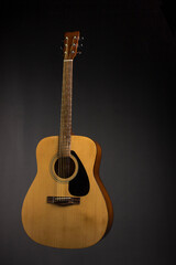 Naklejka premium acoustic guitar made of light wood on a black background. close-up.