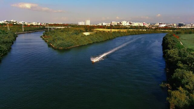 4K drone footage of Condado Lagoon, San Juan, PR. Right panoramic view tracks a jet ski, showcasing vibrant waters and skyline. Ideal for tourism, adventure, lifestyle.
