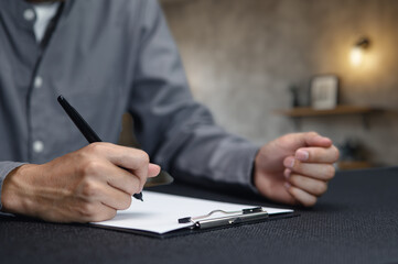 Person Signing Documents on Clipboard in Office Environment