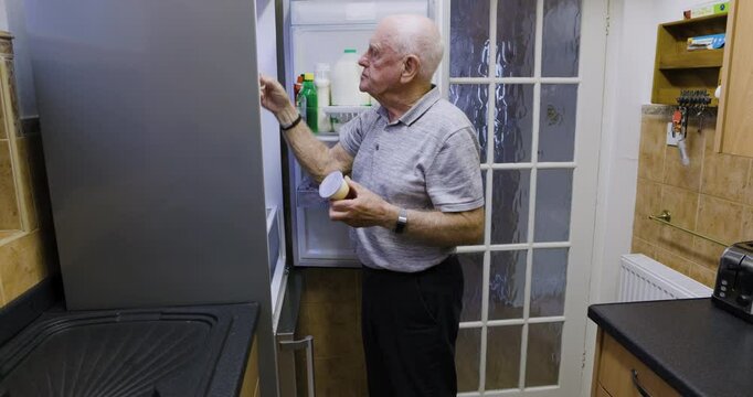 Senior man, packing fridge and grocery in home, dairy product and electric appliance in kitchen. Elderly male, retired and retirement life, food and restock the refrigerator in house with container