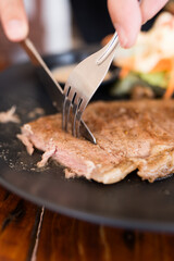 Use fork and knife eating grilled pork chop. Close up