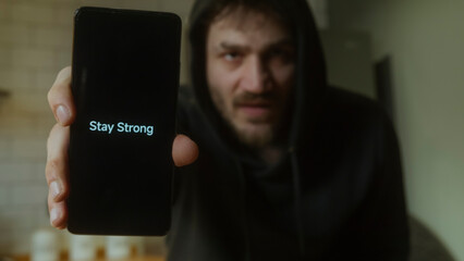 Man Holding Smartphone Displaying Stay Strong Message Motivation and Support Concept