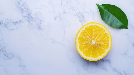 A fresh lemon half and a green leaf rest on a light marble surface with a minimalist background.