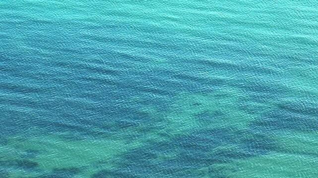 A stunning aerial view captures the tranquil beauty of tropical sea waters, with a harmonious blend of turquoise hues and gentle ripples, inviting awe and peace in this natural wonder.
