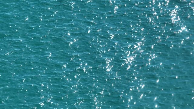 A stunning aerial view captures the vibrant movement of tropical sea waves, where sunlight reflects off the water’s surface, creating a shimmering effect and showcasing the beauty of nature in motion.