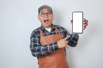 Surprised young Asian man barista barman employee wearing brown apron work in coffee shop using...