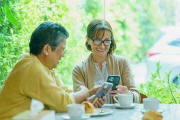 Elderly woman wearing glasses using a phone with friends 