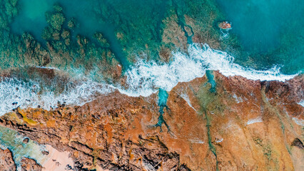 Turquoise water crashing over rocks, a scenic coastal background for summer use.