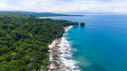 Stunning tropical beach scene with rocks, trees, and turquoise ocean.