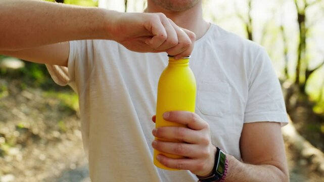 Yellow water bottle being opened outdoors with a person in casual clothing