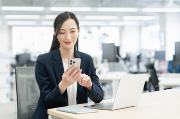 オフィスでスマホを操作する若いビジネスウーマン