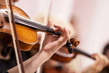 Close-up of a musician's hand playing the violin in an orchestra
