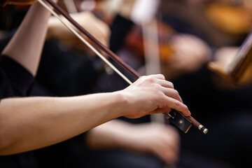 Close-up of a musician's hand playing the violin in an orchestra