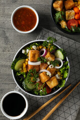 Fried tofu salad with sauces on a wooden background