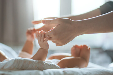 Close-up of infant baby hand grasping parent’s finger – tender moment of love, security, care and family connection, protection in early childhood