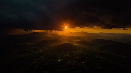 Dramatic golden sunset shining over layered mountains covered in trees