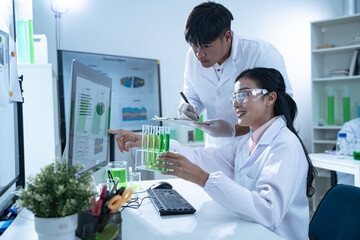 Young scientists analyze test tube results comparing them to computer data in a modern lab environment aiming to advance knowledge and scientific innovation