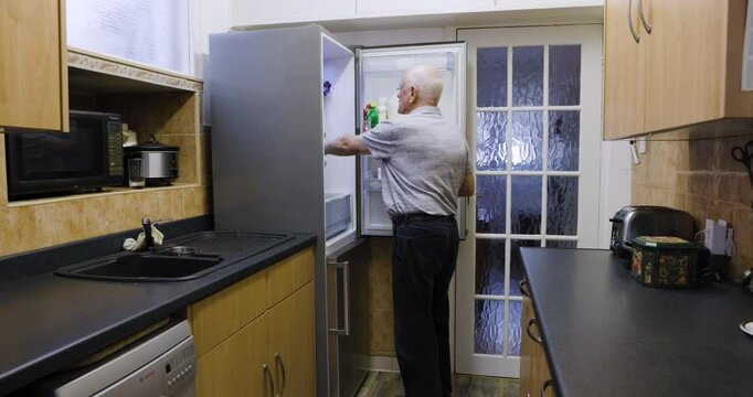 Kitchen, food and senior man in his fridge for ingredients to cook dinner, lunch or supper at home. Hungry, eating and elderly guy in retirement looking for snacks to eat in a refrigerator at a house