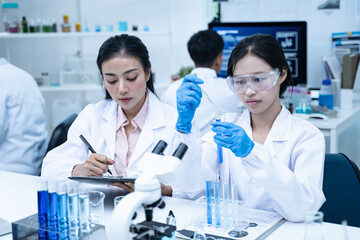Scientist in laboratory conducting medical research using modern science and technology while taking note for doctor and clinical analysis.