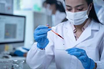 In the laboratory, several researchers conduct blood tests and analysis on samples, using science...