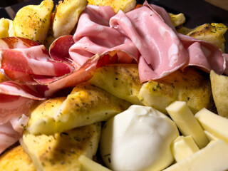 Traditional Italian food. Mix of typical cheeses and cold cuts on a wooden cutting board. Delicious food. Aperitif or starter of home made food