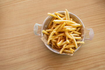 French fries placed in a metal tray on a wooden table with space for copying